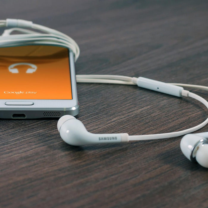 Samsung white wired in-ear earbuds with Galaxy phone showing Google Play Music